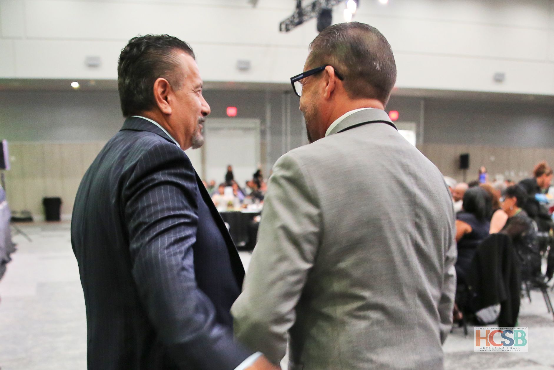 Two men in suits are shaking hands in a conference room.
