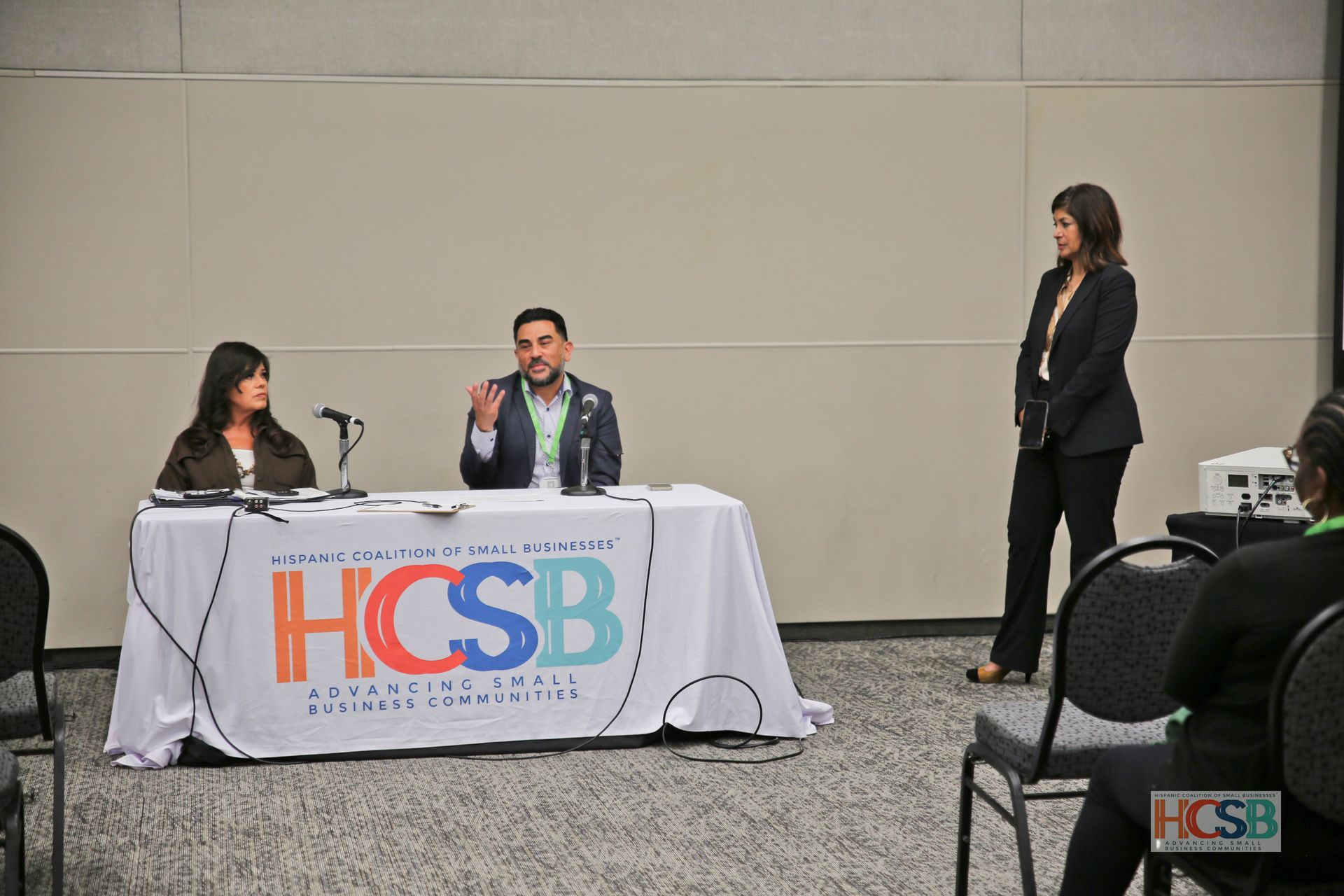 A group of people sitting at a table with a hcsb sign on it