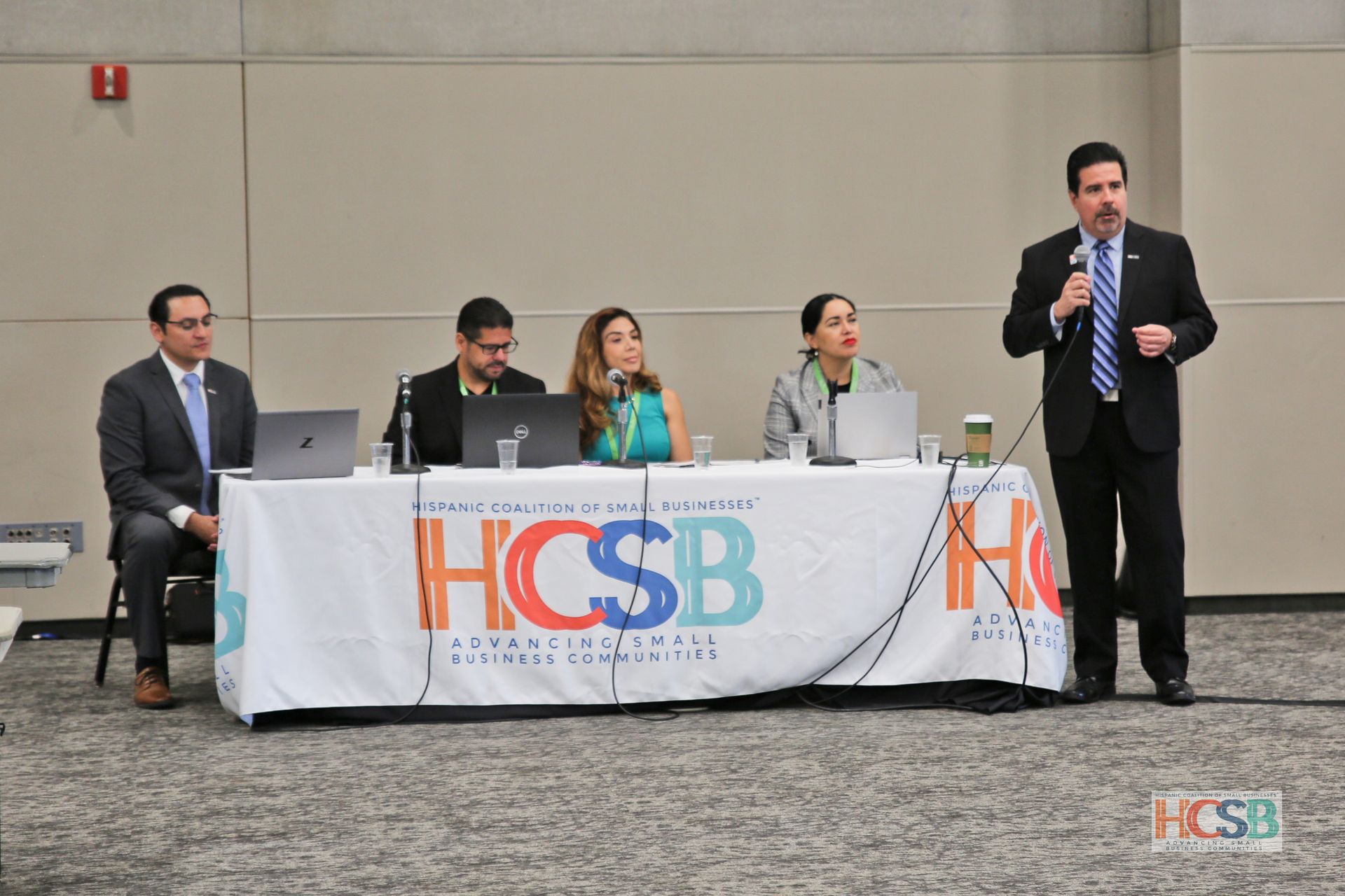A group of people sitting at a table with a sign that says hcsb