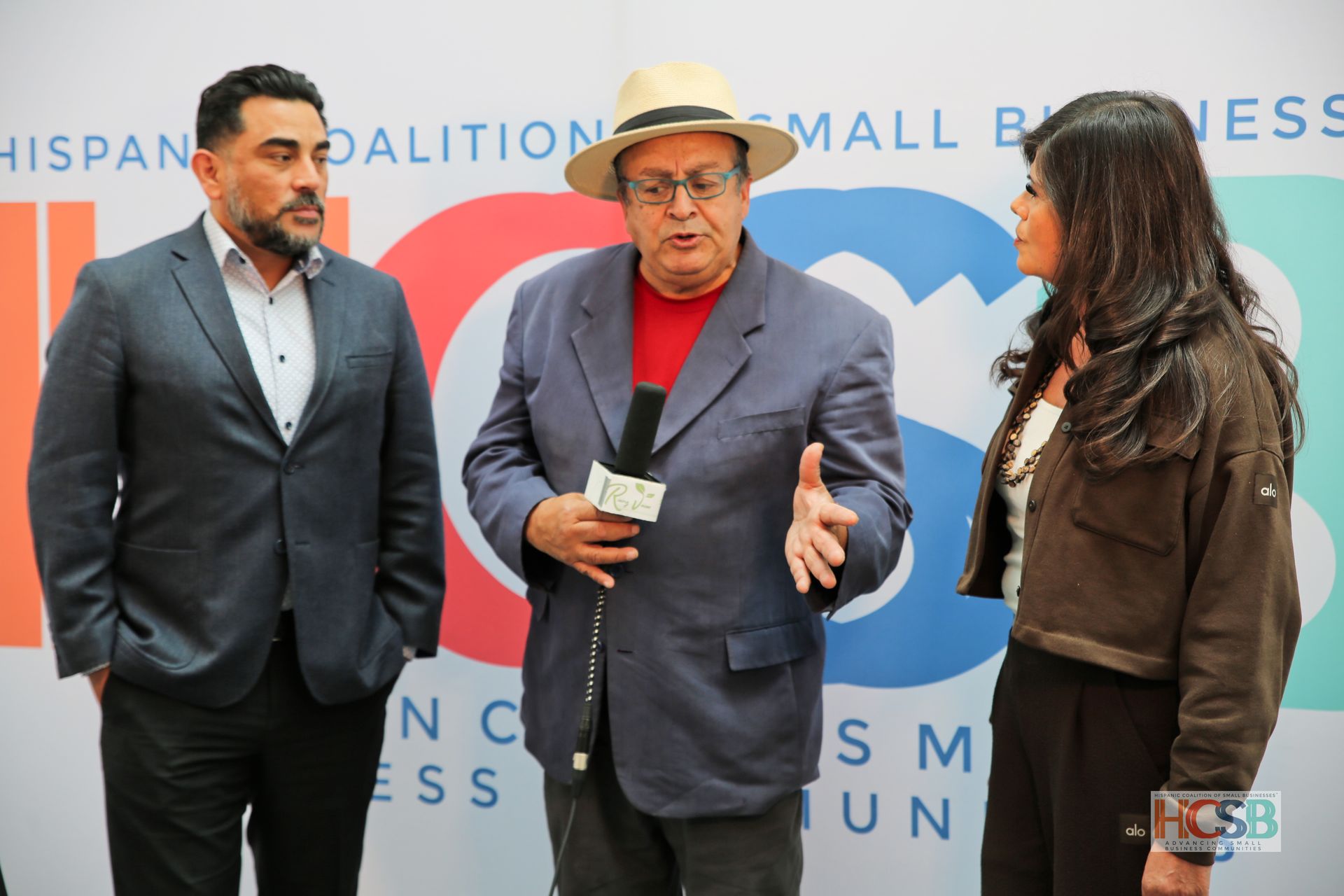 Three people are standing in front of a sign that says hispanic coalition