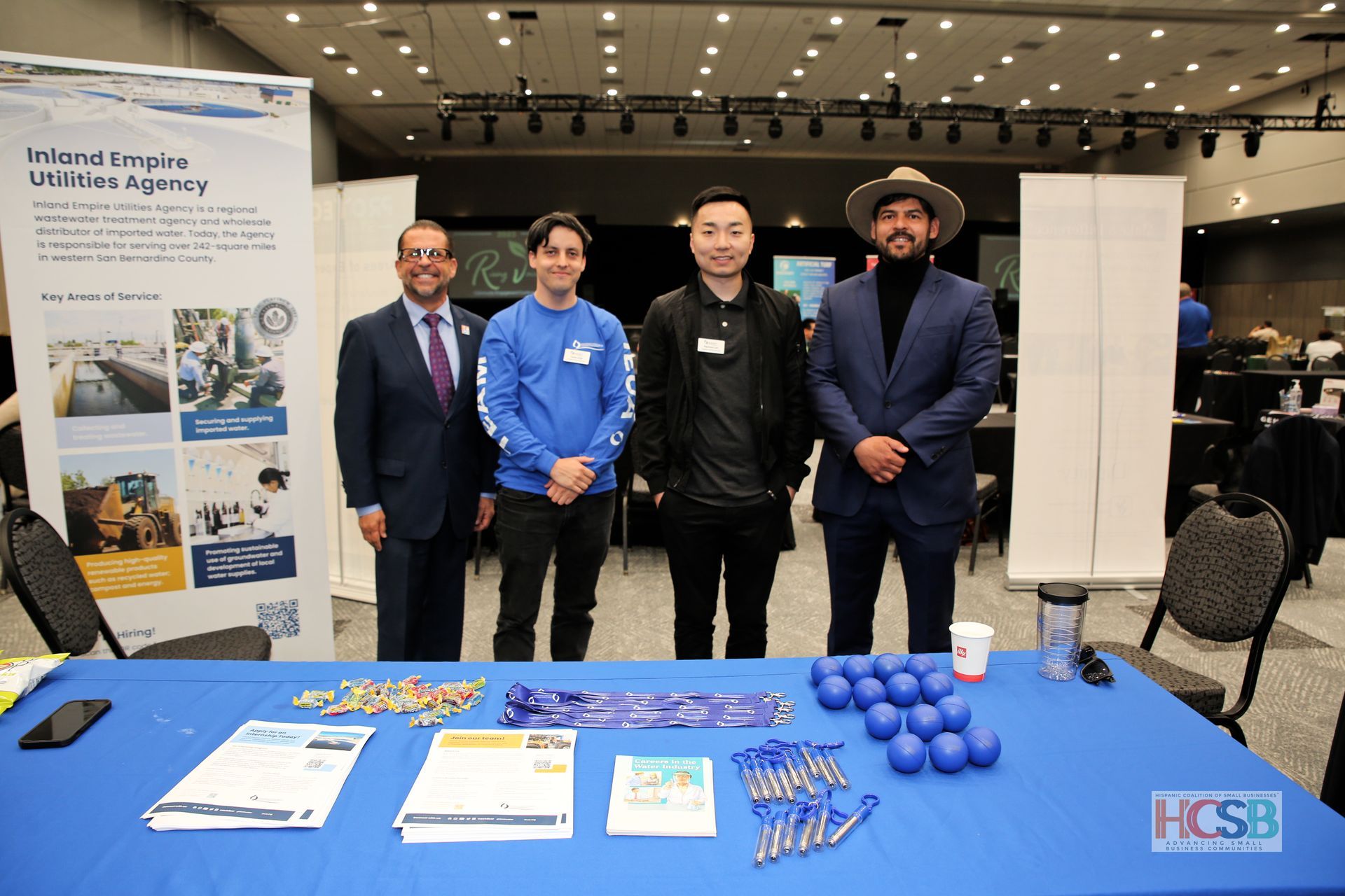 A group of men are standing around a table at a job fair.