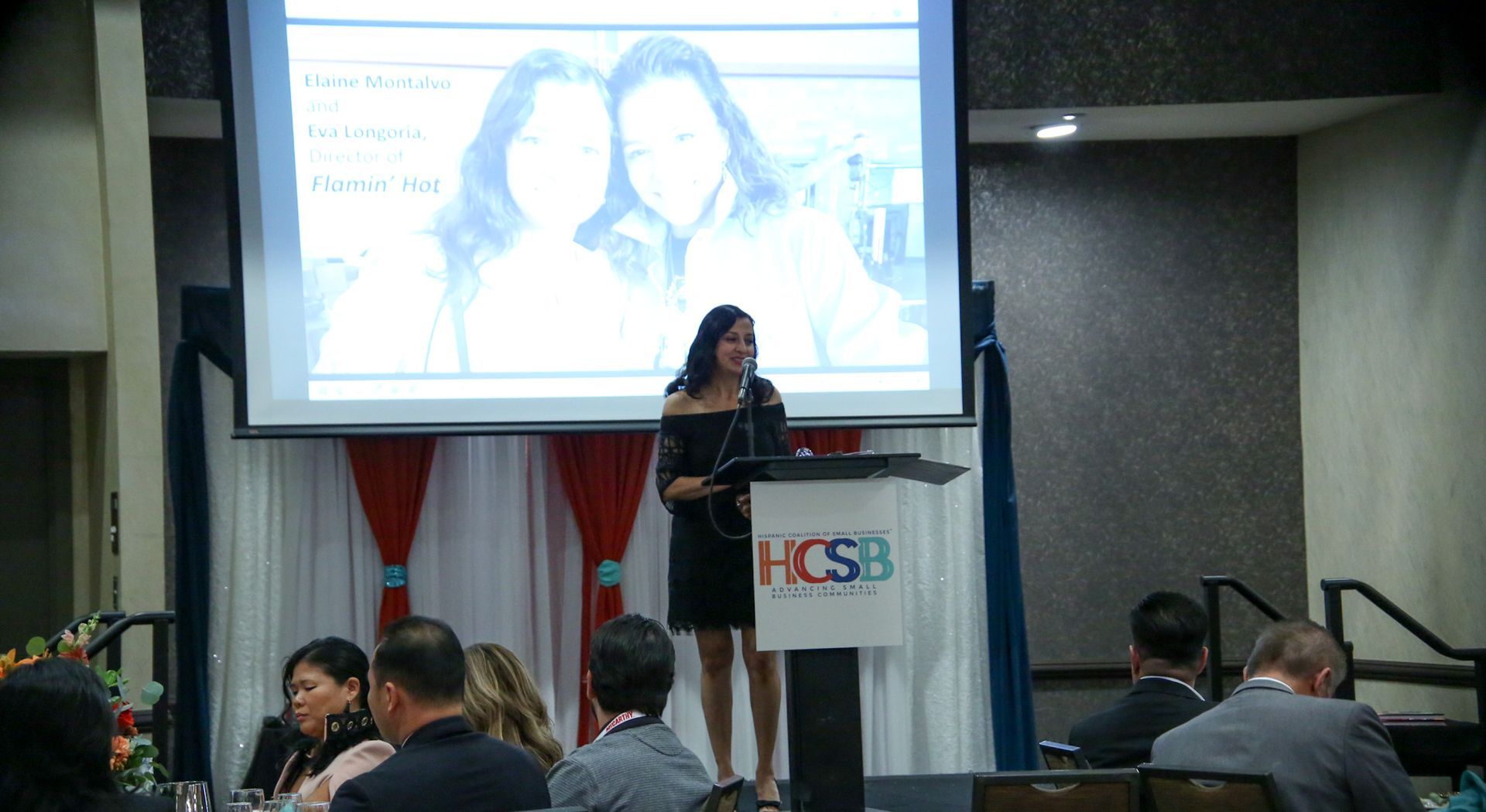 A woman is standing at a podium giving a presentation to a group of people.