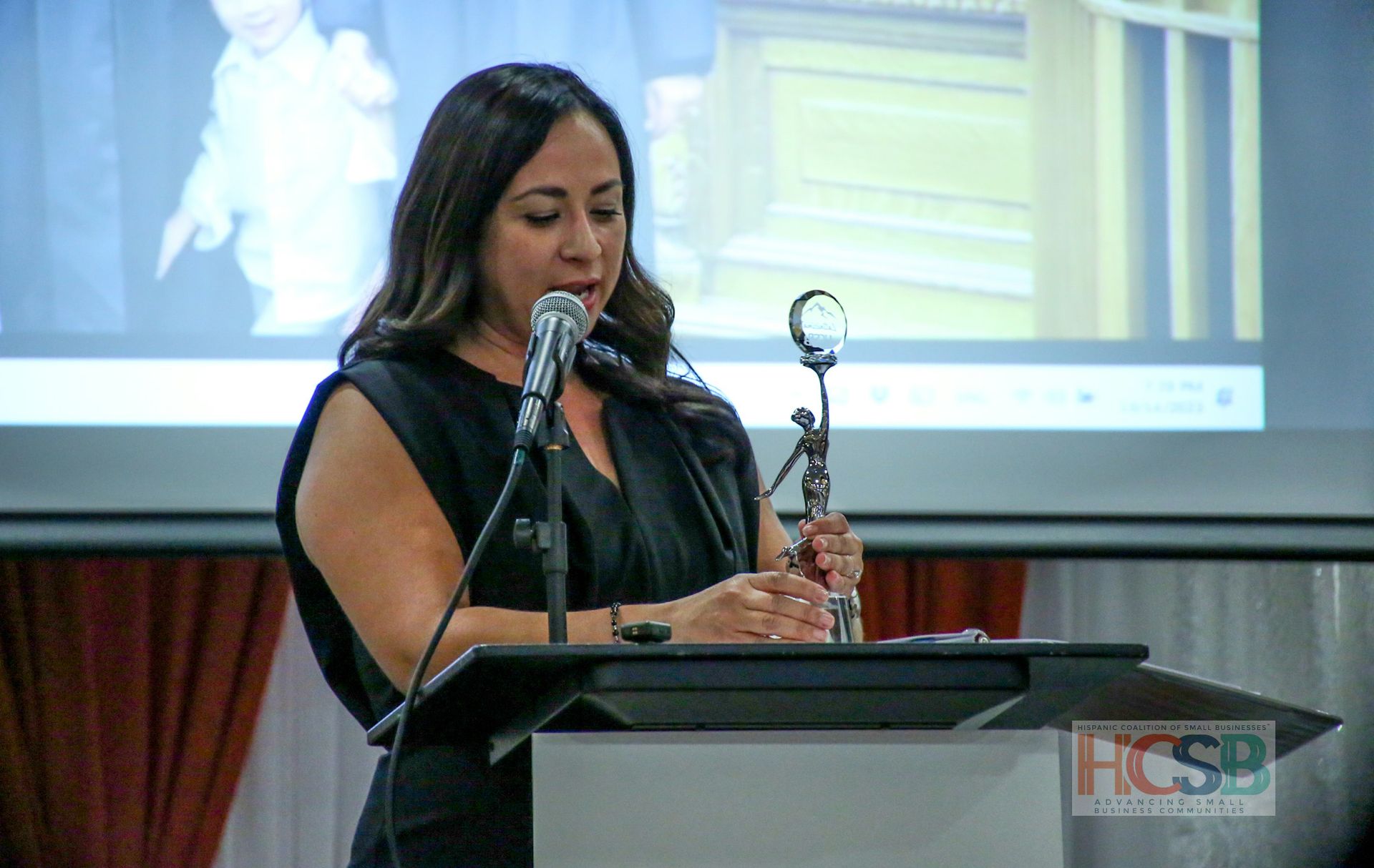 A woman is standing at a podium speaking into a microphone.