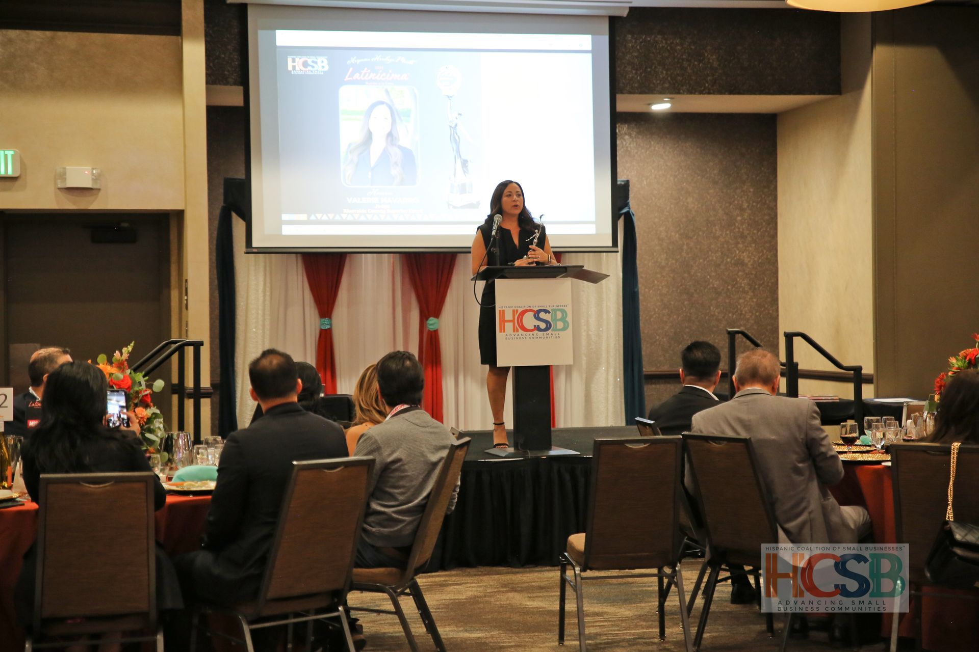A woman is standing at a podium giving a presentation to a group of people.