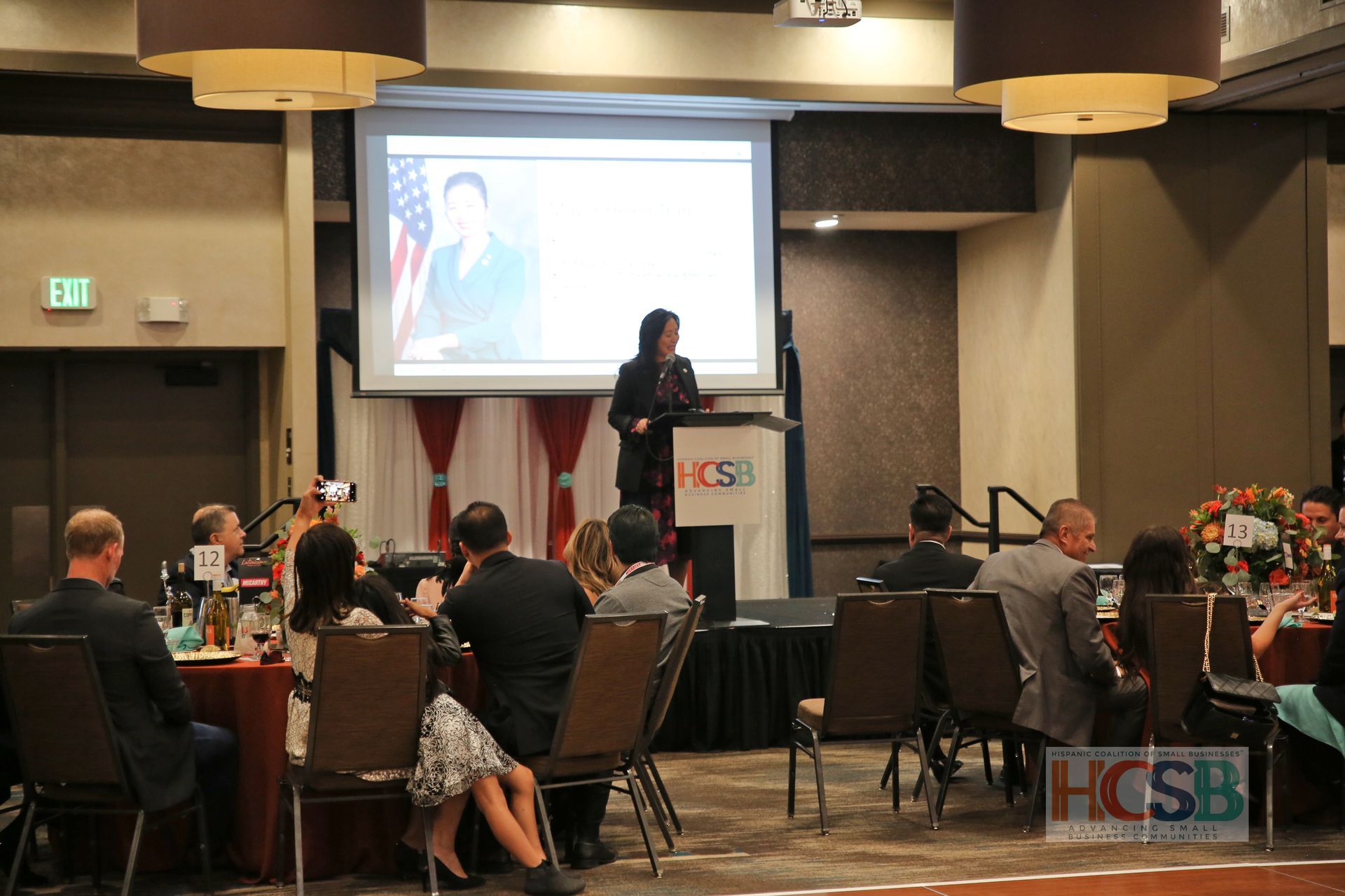 A woman is standing at a podium giving a presentation to a group of people.