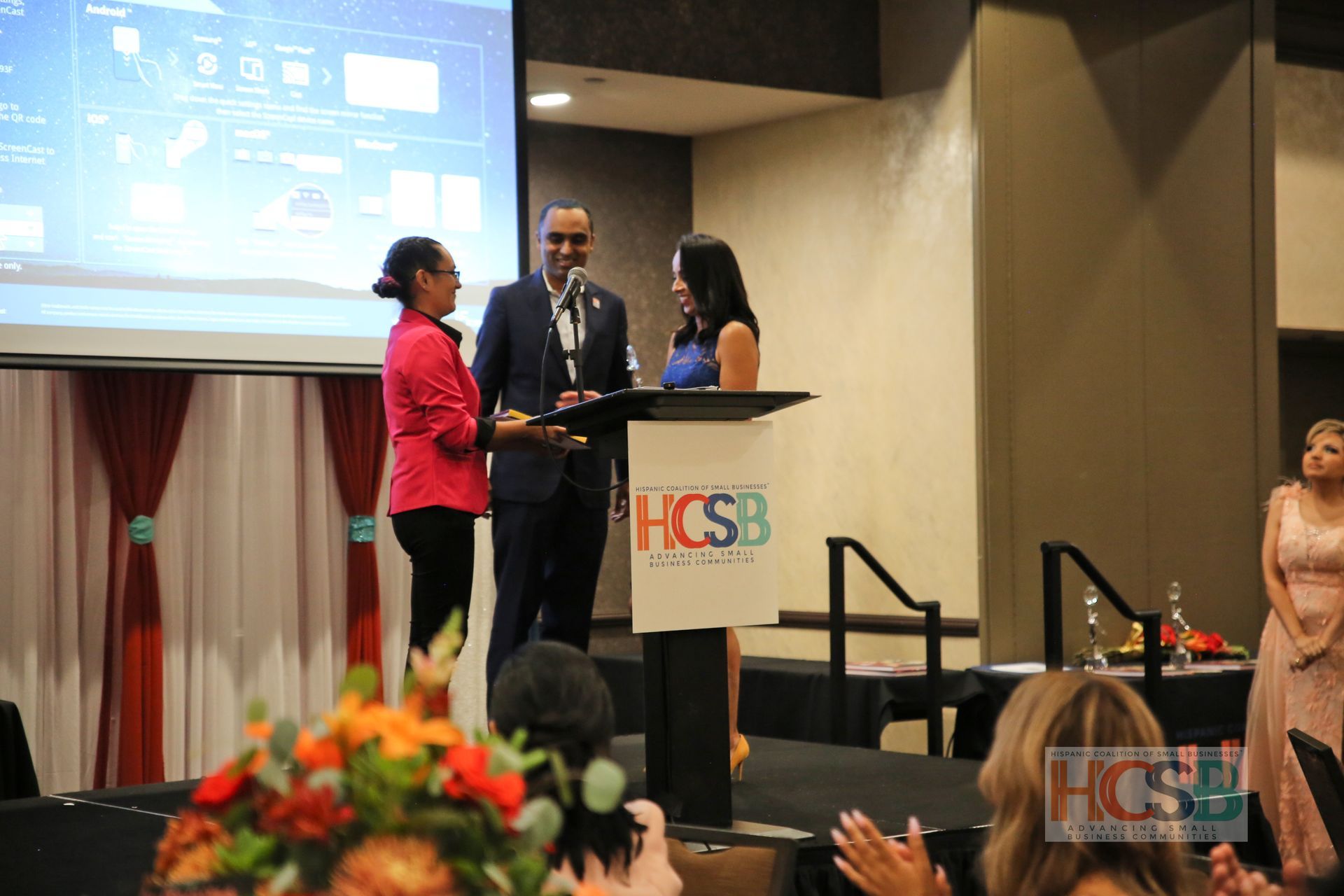 A man and a woman are standing at a podium in front of a crowd.