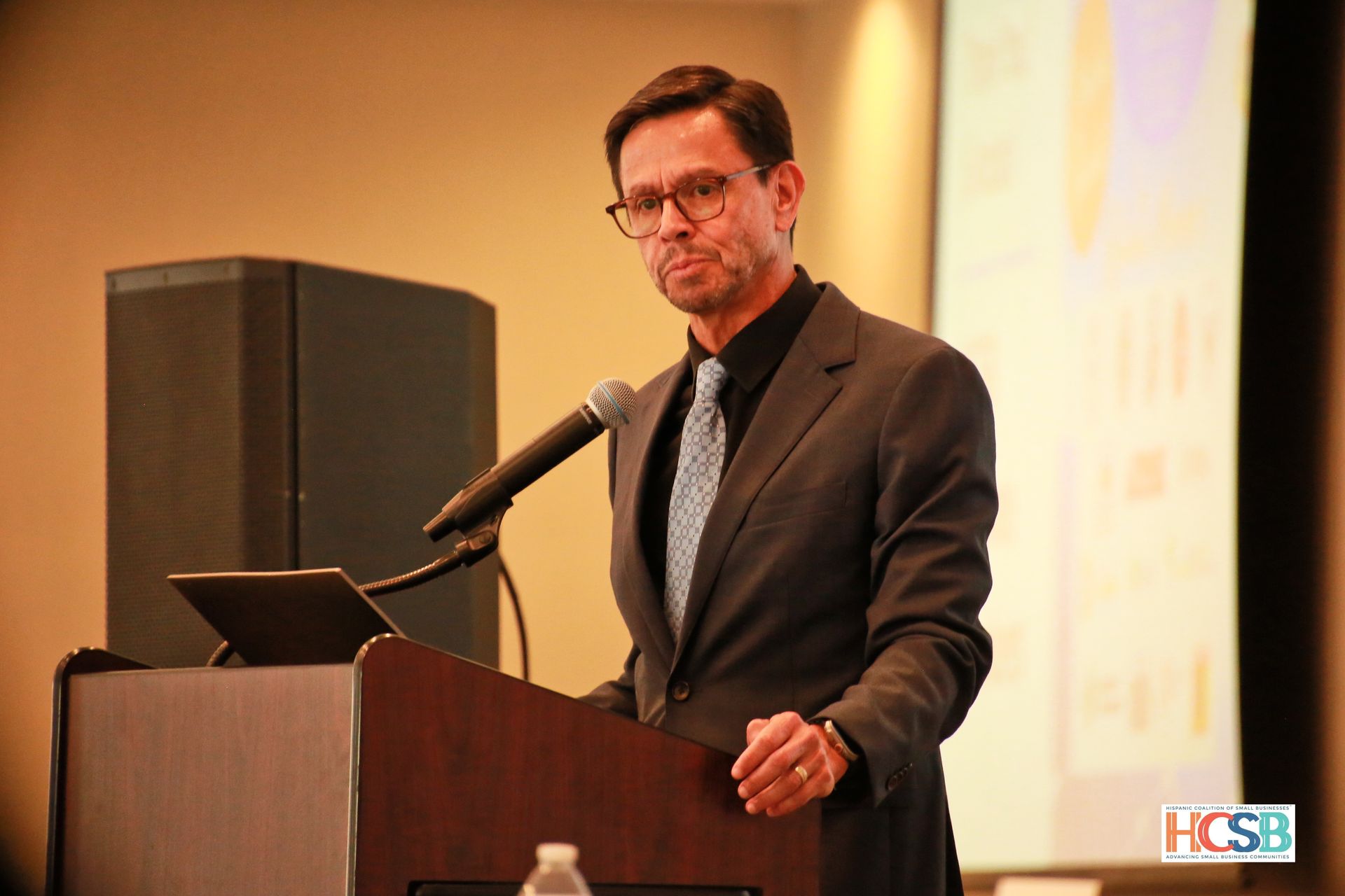 A man in a suit and tie is giving a speech at a podium