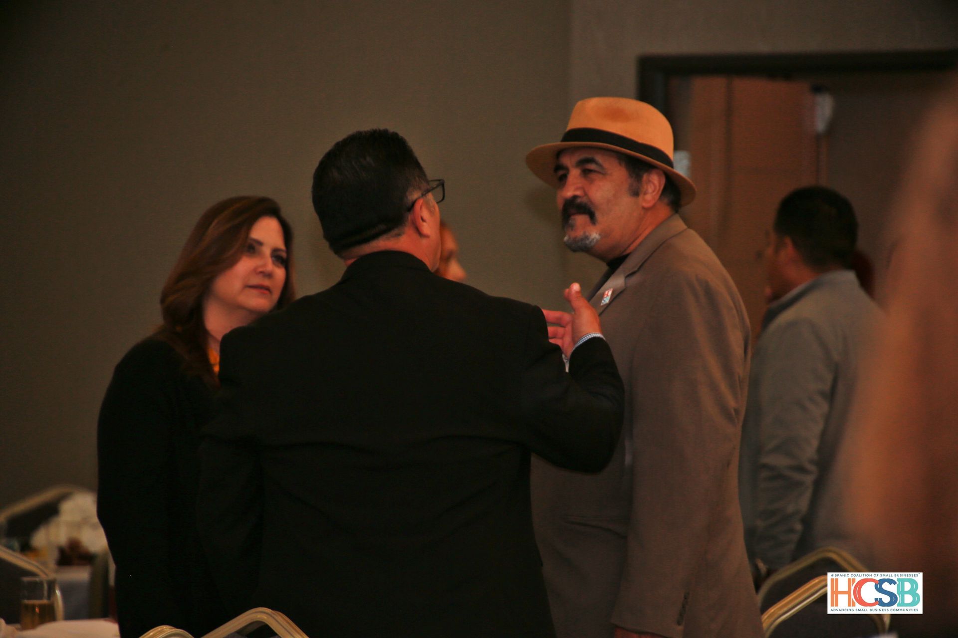 A group of people are standing in a room talking to each other.