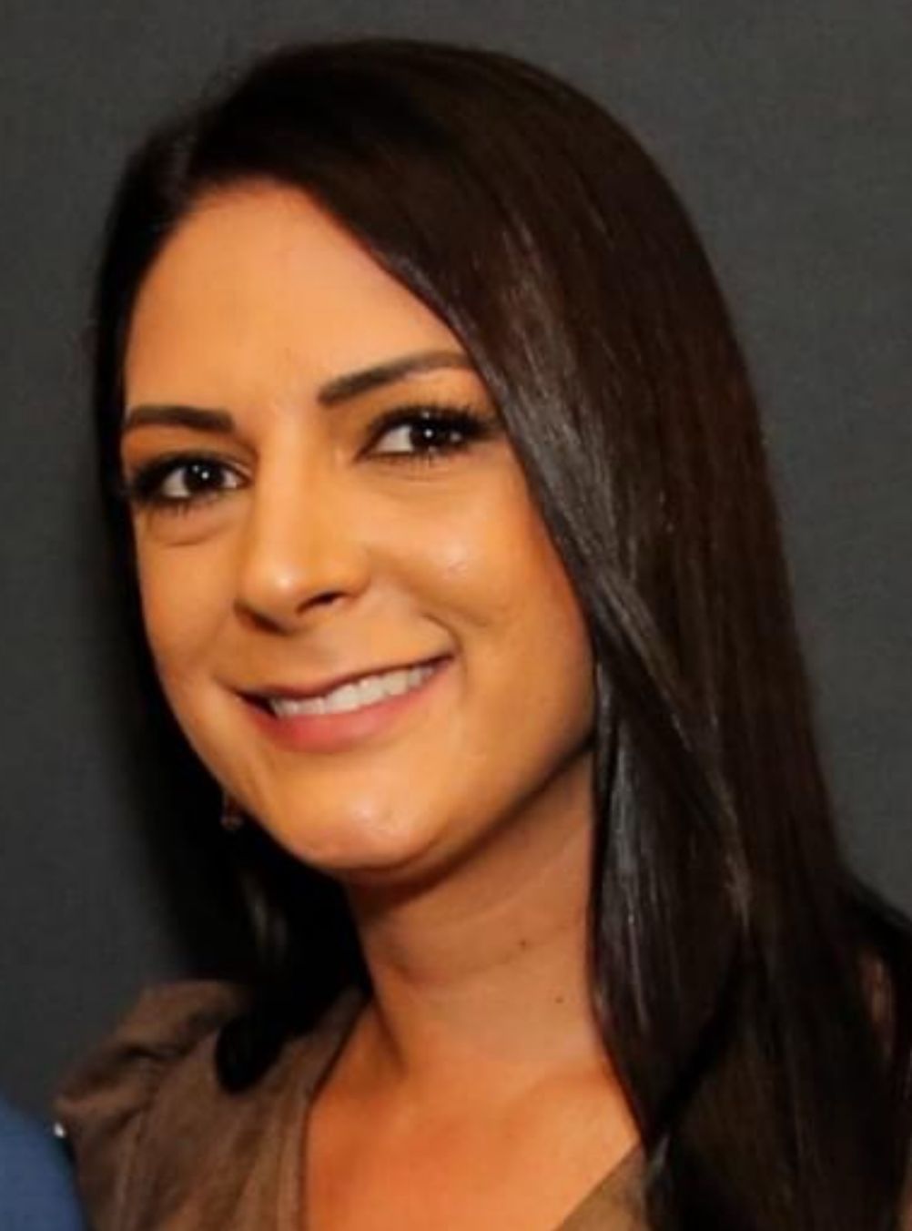 A woman with long dark hair is smiling for the camera