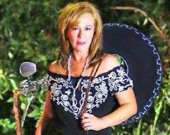 A woman is wearing a sombrero and holding a microphone.