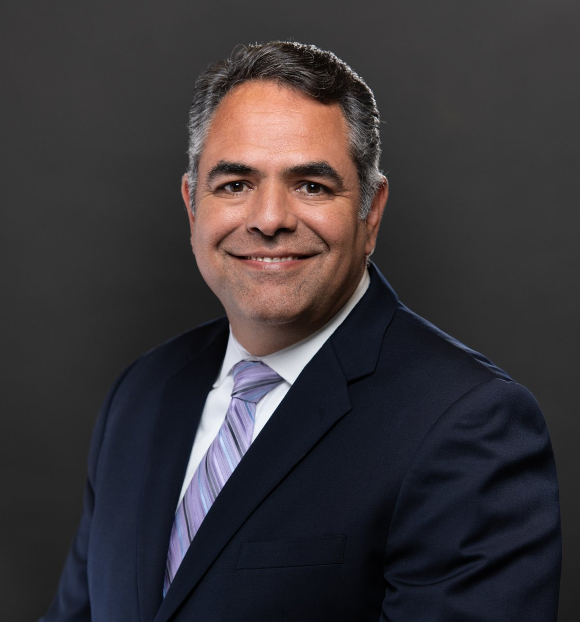 A man in a suit and tie is smiling for the camera.