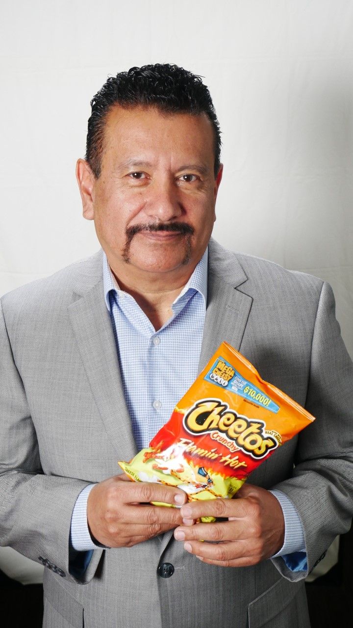 A man in a suit is holding a bag of cheetos