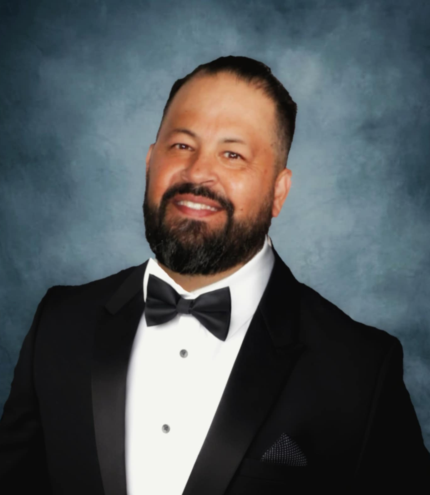 A man in a suit and plaid shirt is smiling for the camera.
