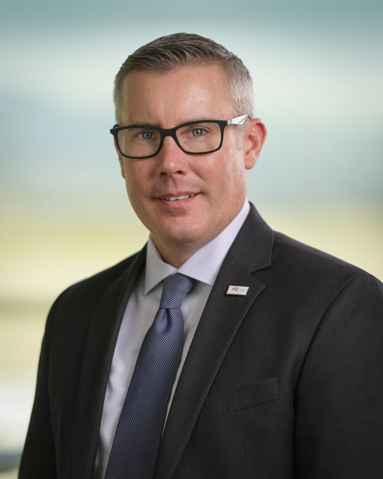A man in a suit and tie is smiling for the camera.