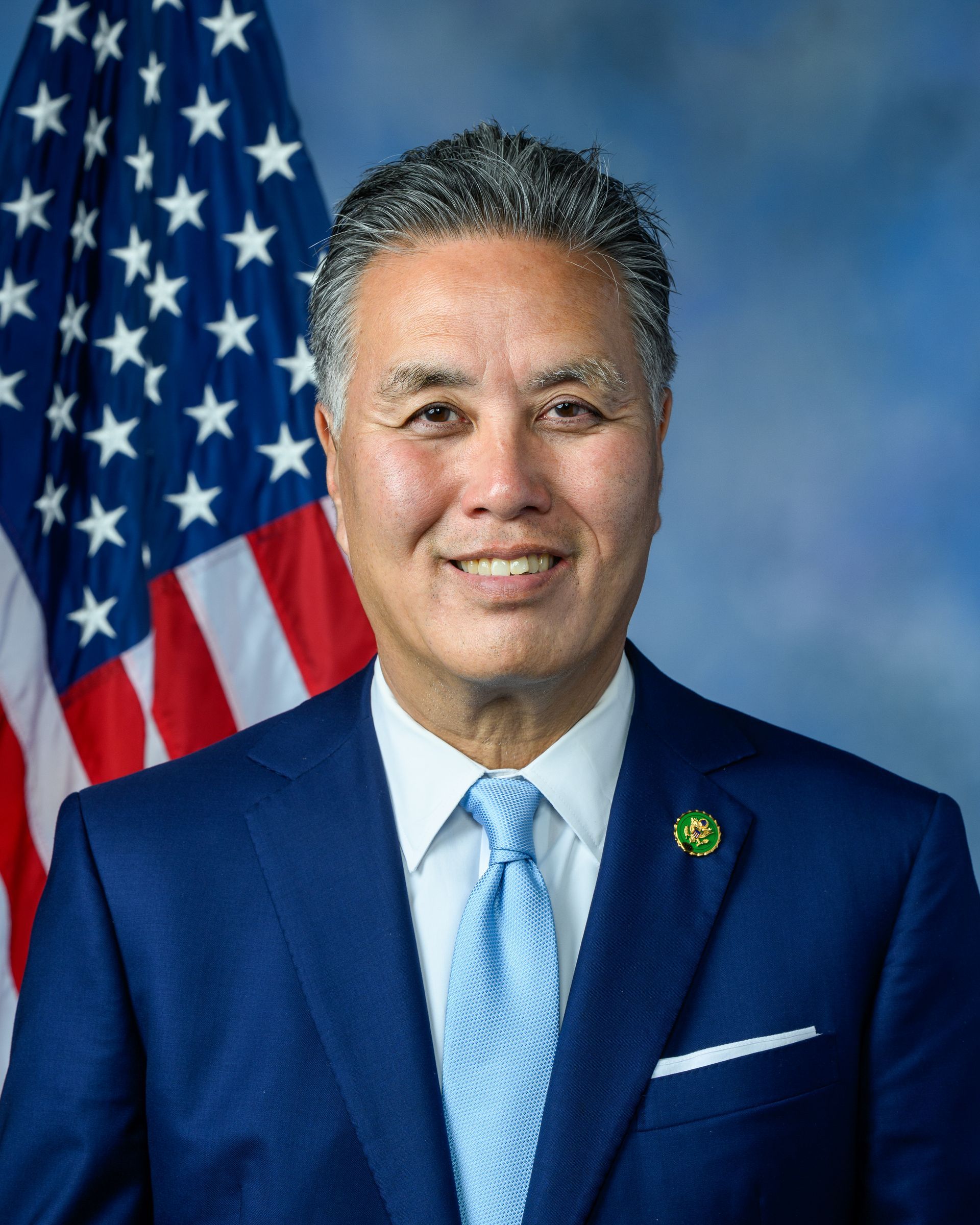 A man in a suit and tie is standing in front of an american flag.