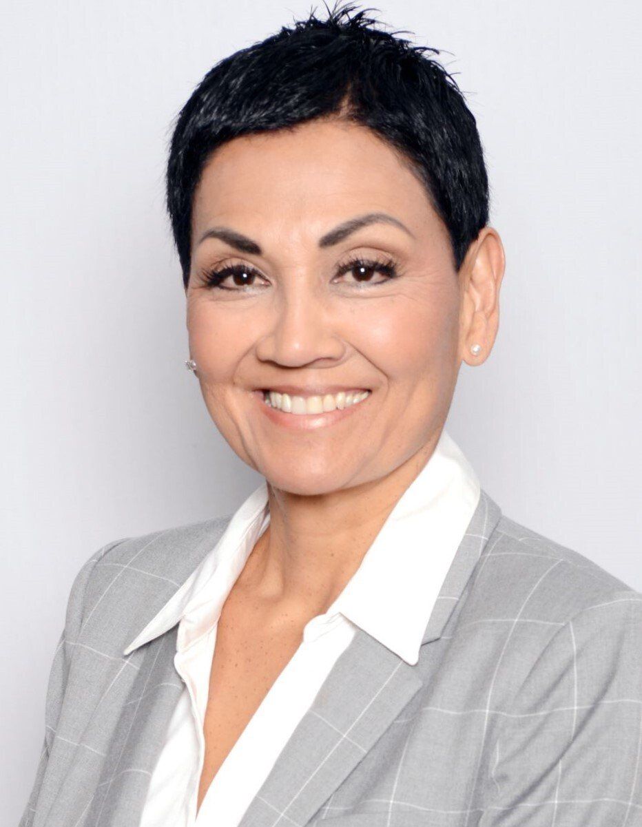A woman in a suit and white shirt smiles for the camera