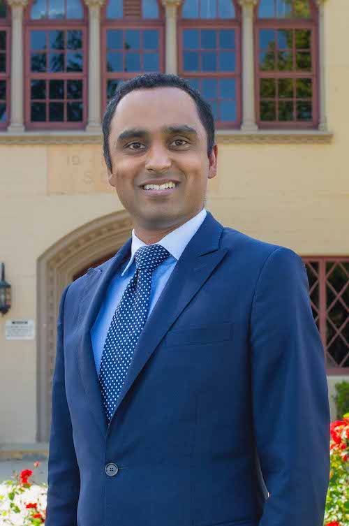 A man in a suit and tie is standing in front of a building.