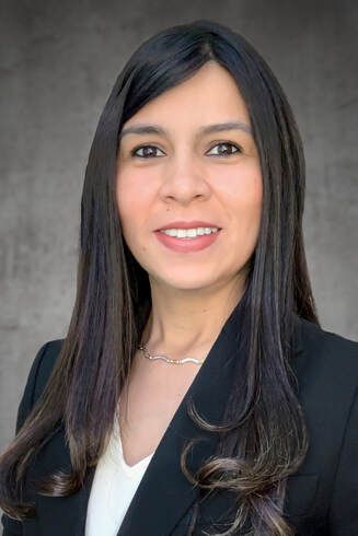A woman in a black jacket and white shirt is smiling for the camera.