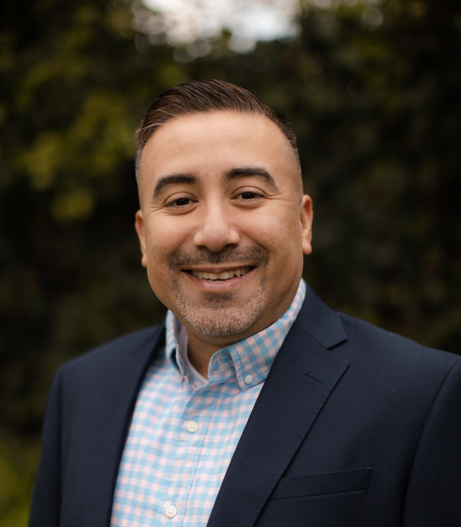 A man in a suit and plaid shirt is smiling for the camera.