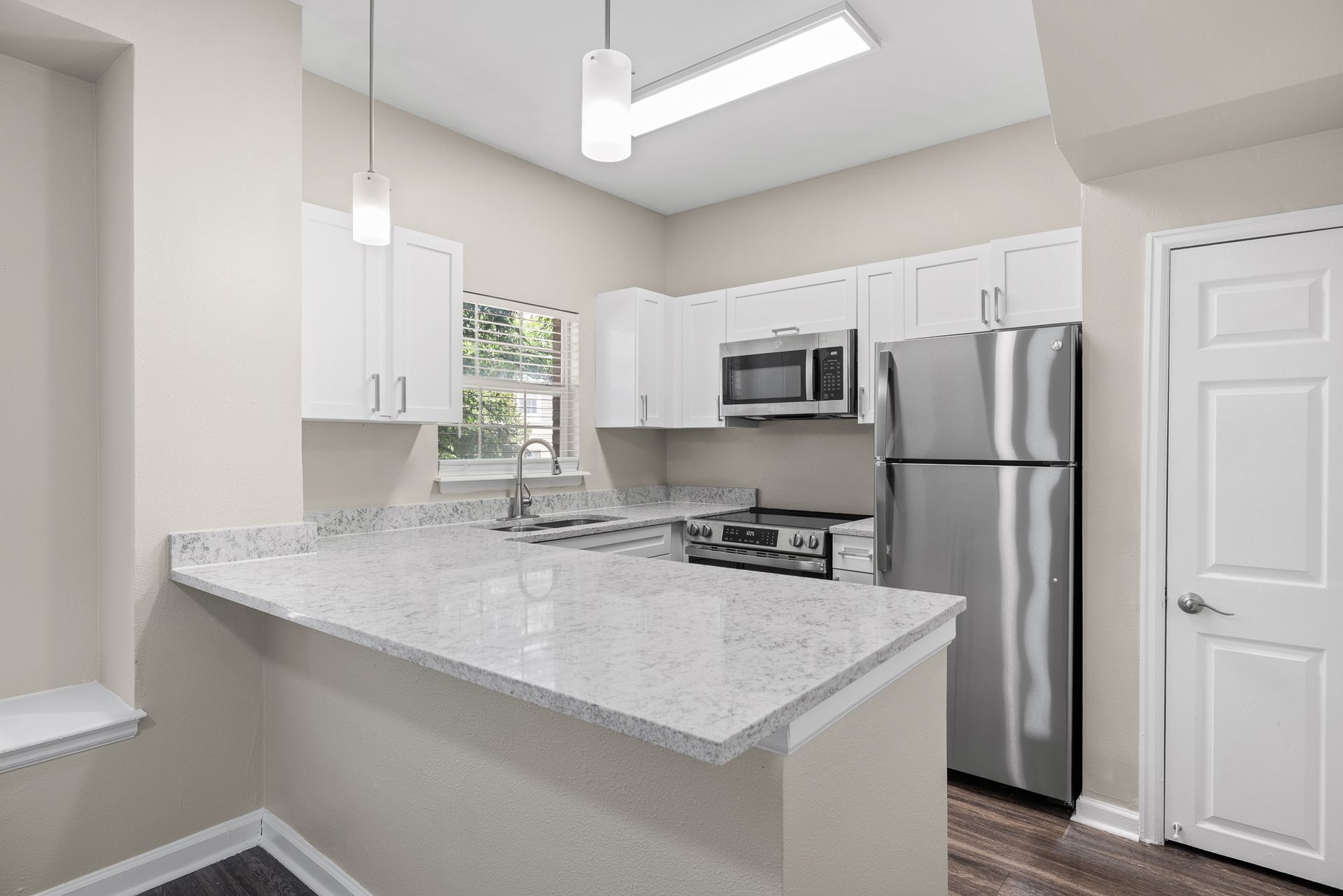 Bright modern kitchen with white cabinets, stainless appliances, and a gray granite island.