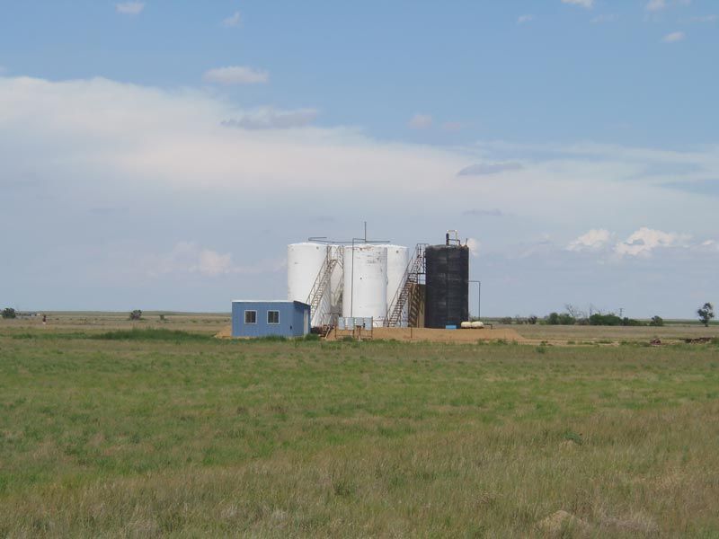 A row of silos are sitting in the middle of a grassy field.