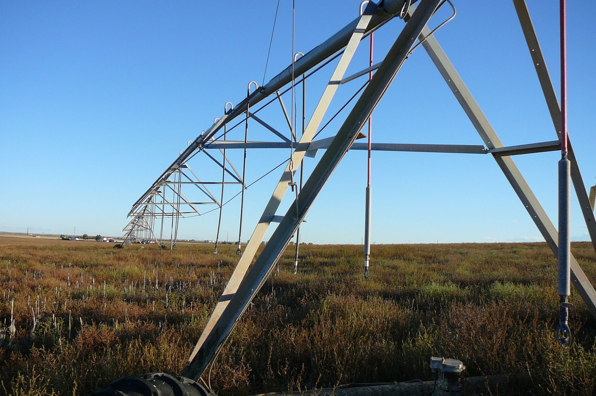 A metal irrigation system in a field, against a blue sky.