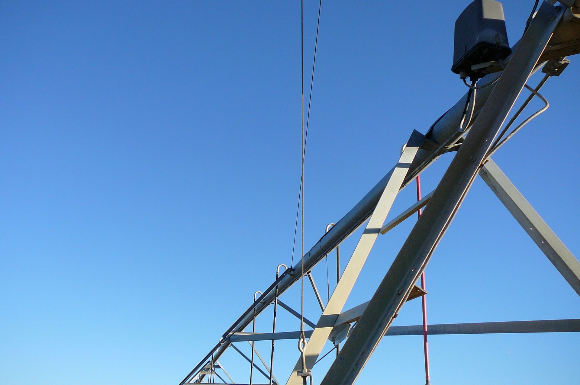 Irrigation system arm against a clear blue sky.