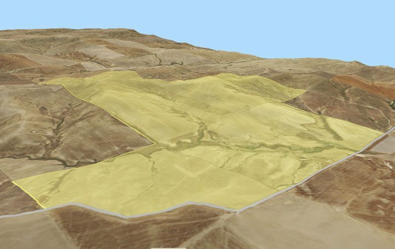 A three-dimensional view of a hillside, highlighting a yellow-tinted agricultural field.