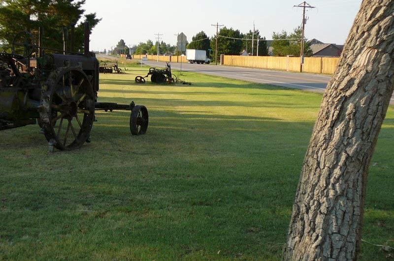 An old wagon is parked in the grass next to a tree