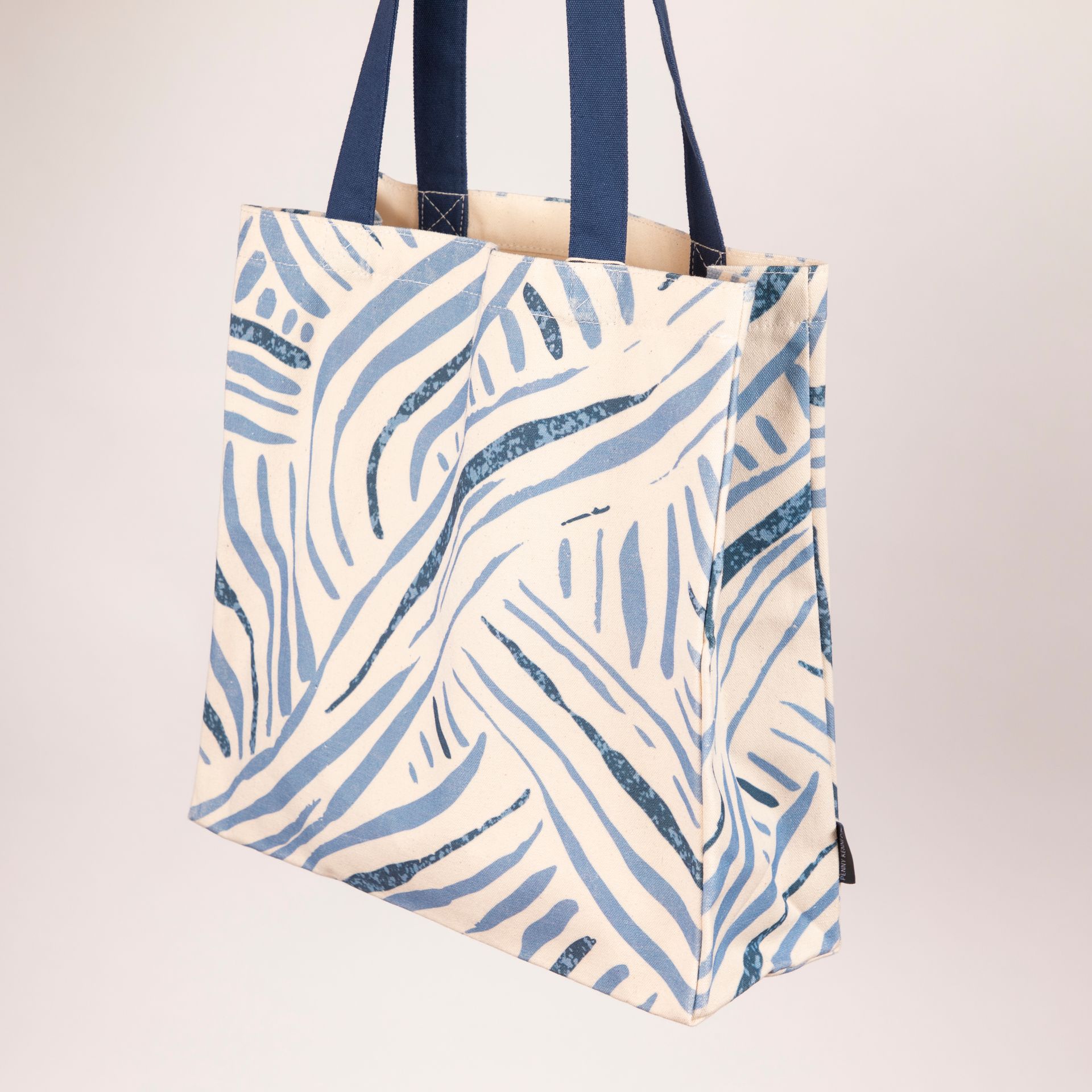 A white and blue tote bag with a Penny Kennedy zebra print on it.