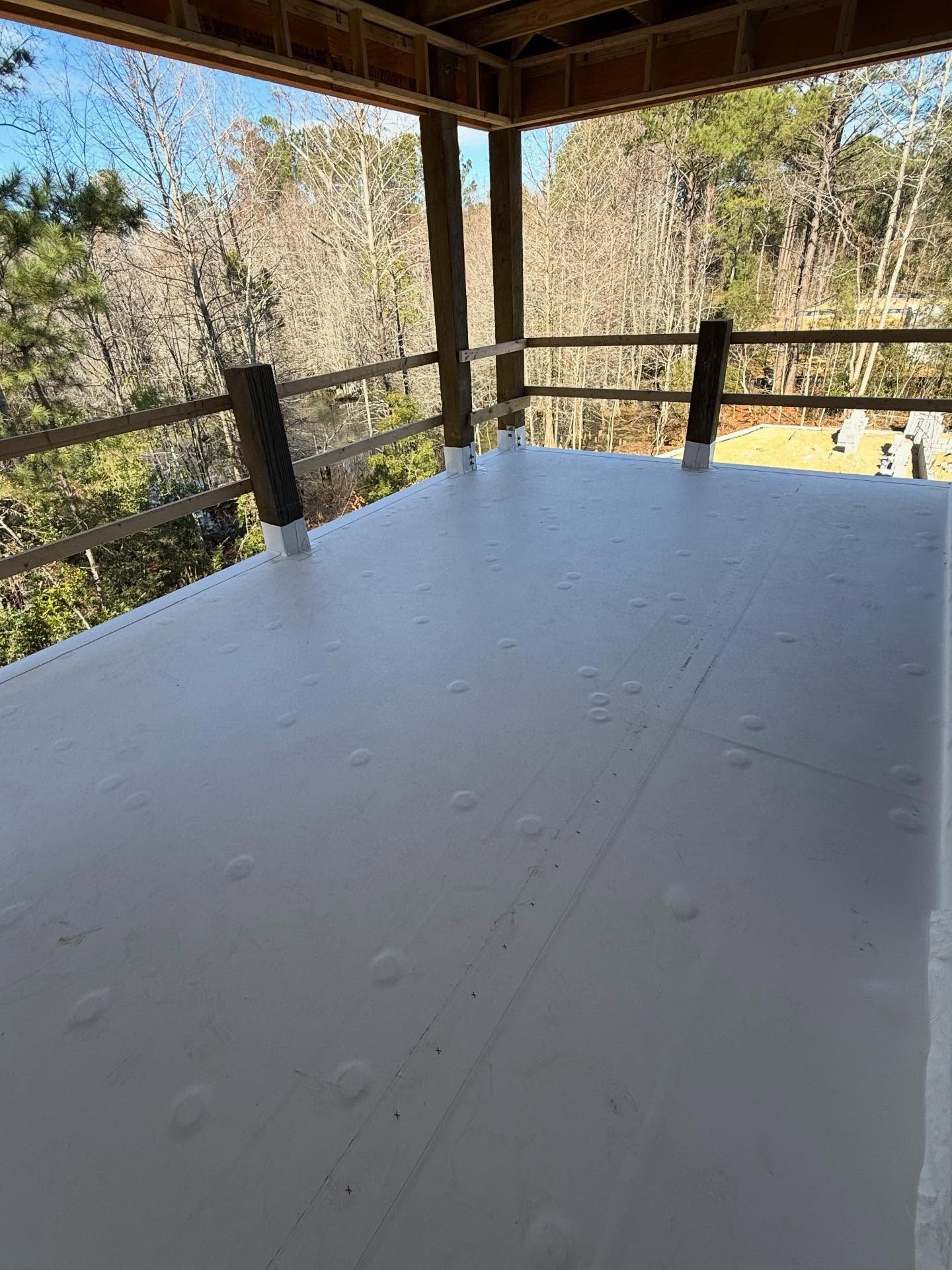 Covered wooden deck with white tabletop overlooking trees and a hillside view
