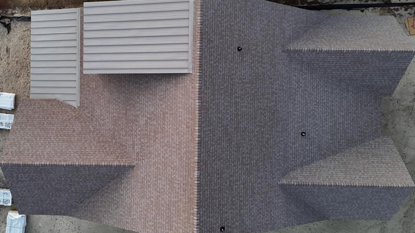 Aerial view of two adjacent rooftops, one tan and one dark gray, with vents and intersecting rooflines.