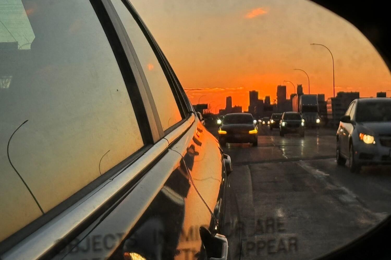 A view of the St. Paul skyline at sunset, heading up north on 35 from the side rearview mirror