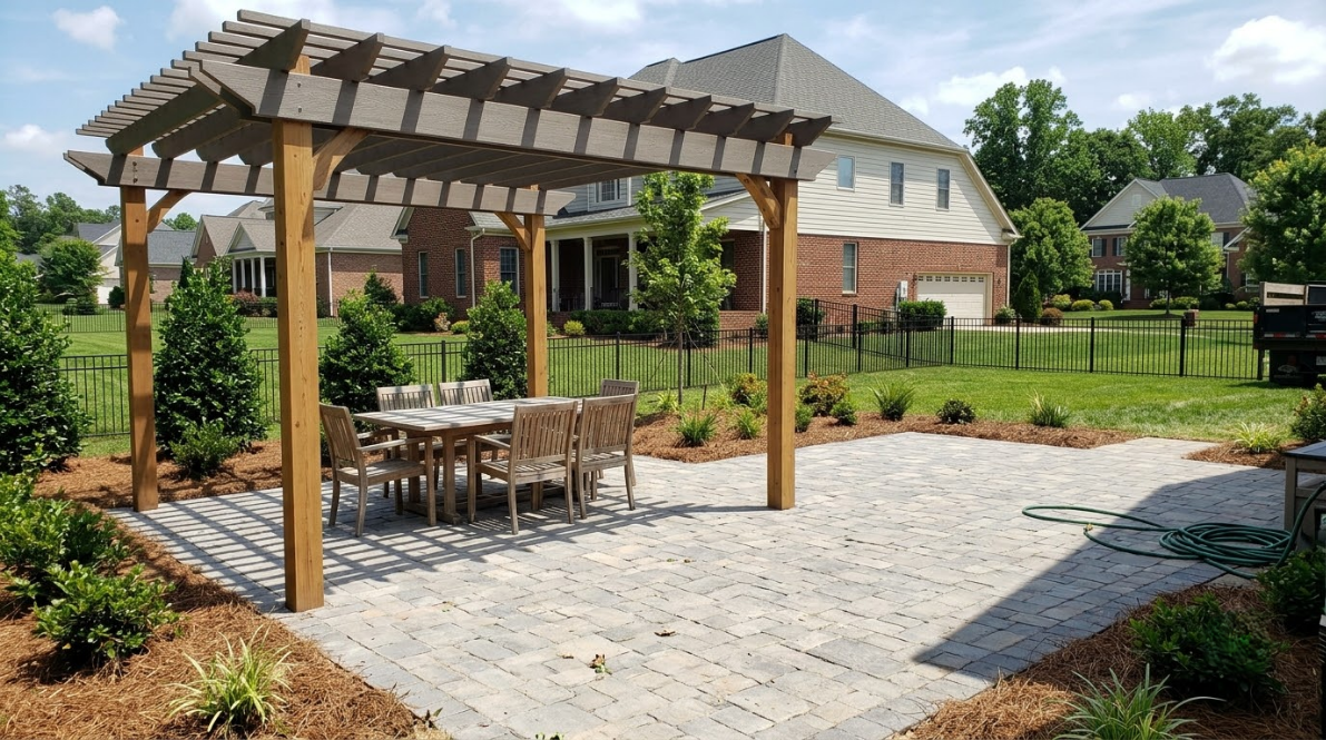 Wooden gazebo with patio dining table on a stone terrace in a landscaped backyard garden.