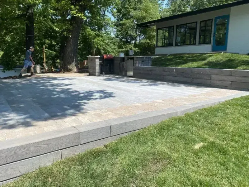 Accessible plaza with a ramp, stone steps, and a building beside a grassy lawn and trees