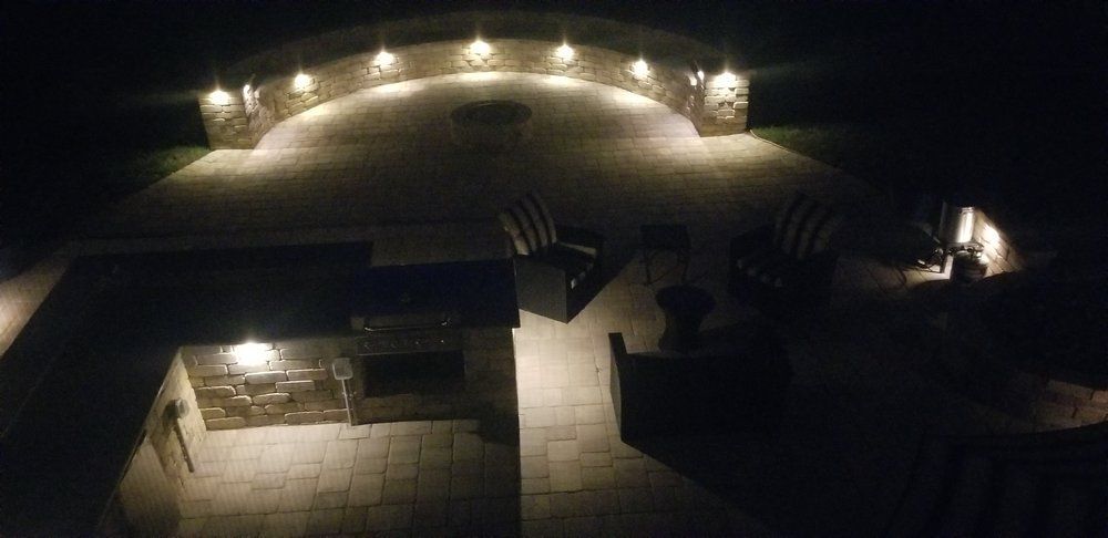 Nighttime patio with warm string lights illuminating a curved walkway and seating area