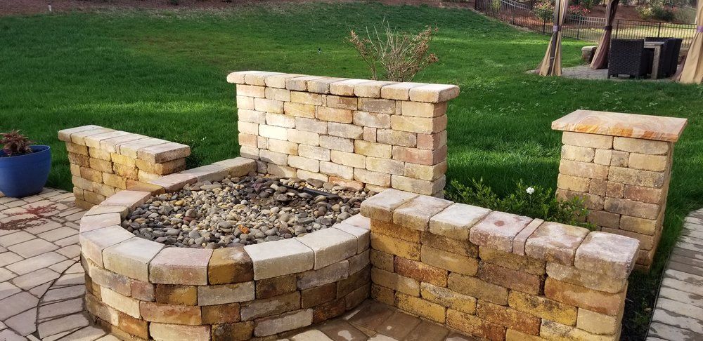 Stone outdoor fire pit with curved bench seating in a backyard patio area