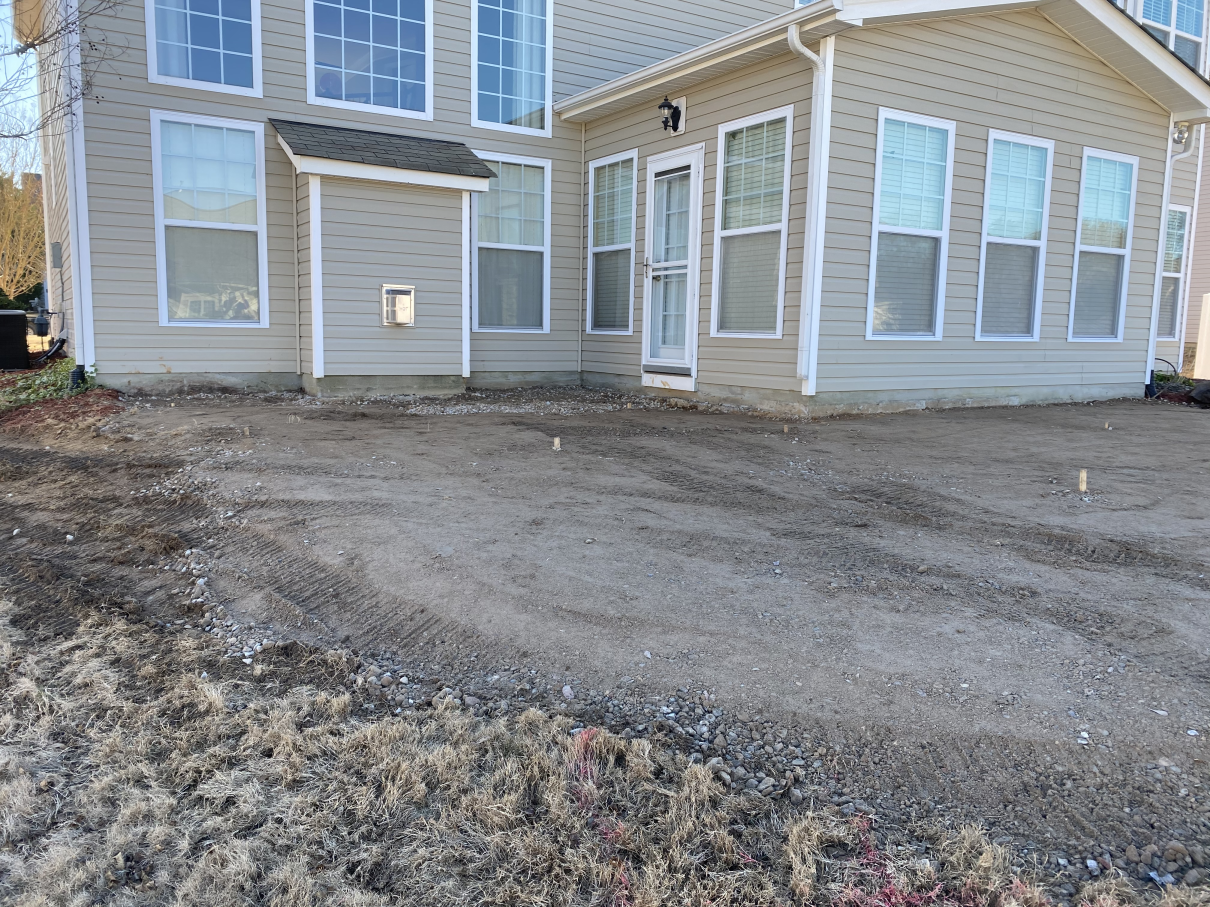 New beige house with white trim and gravel driveway under construction