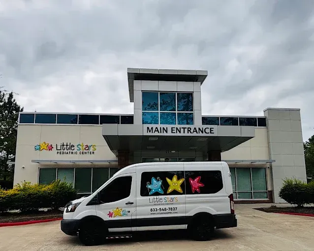 Little Stars Pediatric Center entrance in The Woodlands with a branded transportation van