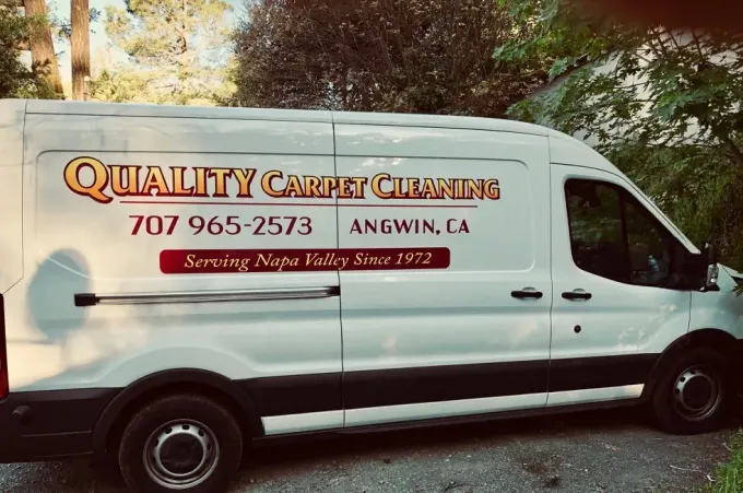 Two white cargo vans parked on a gravel driveway, one branded “Quality Carpet Cleaning” in Auburn, CA.