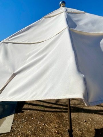 Pyramid of beige cushions on a tarp beside a picnic table outdoors