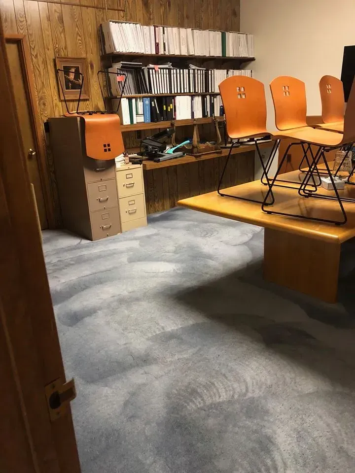 Wood-paneled room with orange chairs on a platform, shelves of binders, and a small filing cabinet