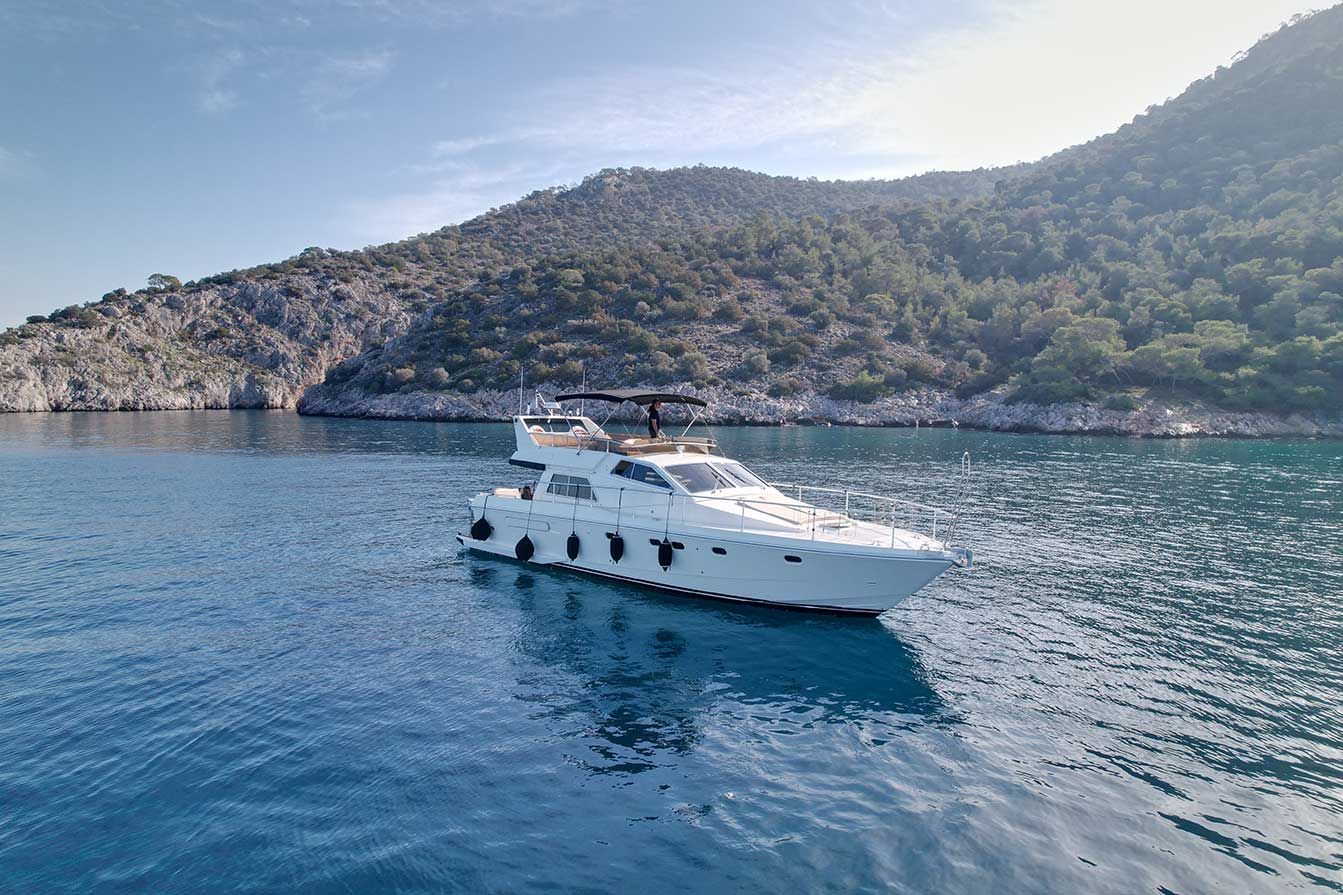 Luxury yacht charter cruising near a scenic Greek island coastline