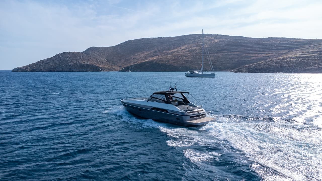 Private motor yacht cruising along the Mykonos coastline with sea views