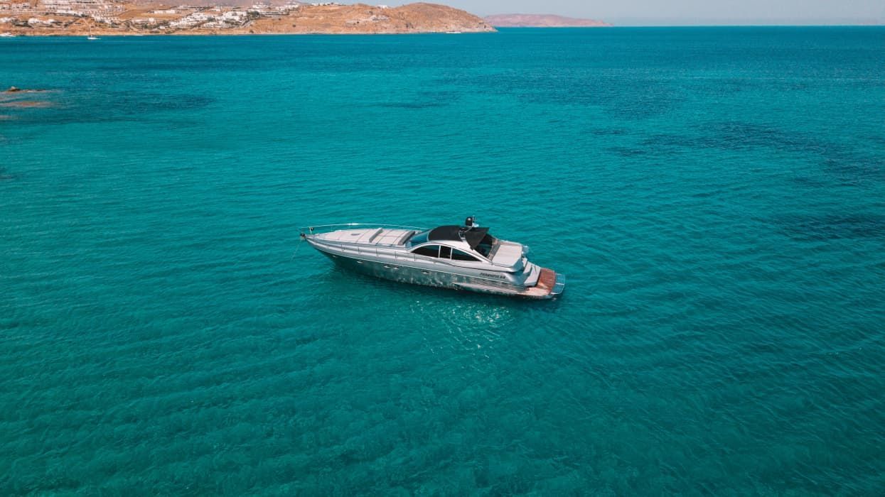 Luxury private boat tour in Mykonos cruising along the south coast near Delos and Rhenia islands