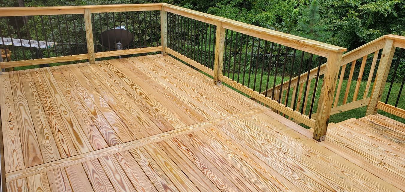 A wooden deck with railings and metal balusters overlooking a lush green yard.
