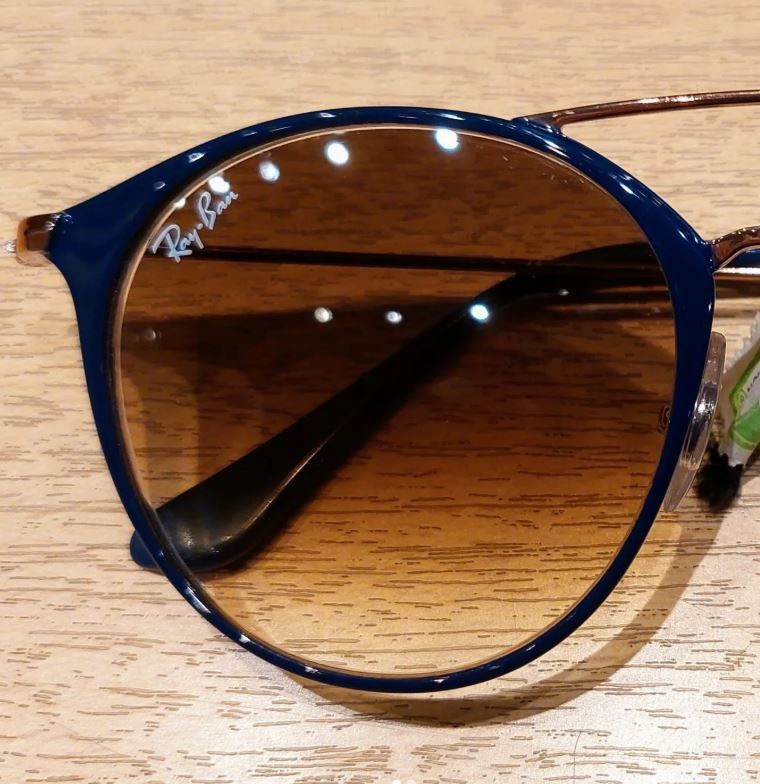 Gafas de sol Ray-Ban azules con lentes espejadas marrones sobre una superficie de madera.