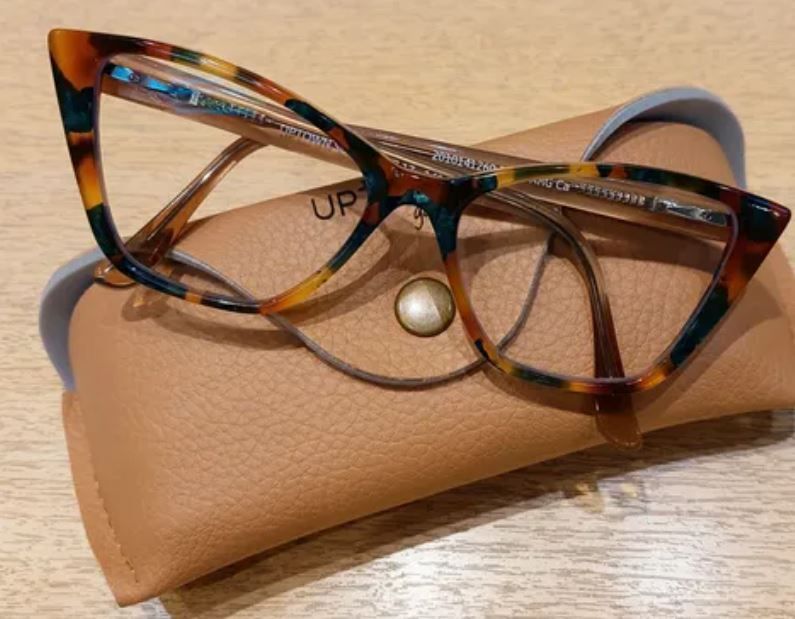 Gafas de carey marrón descansando sobre un estuche color canela sobre una superficie de madera.