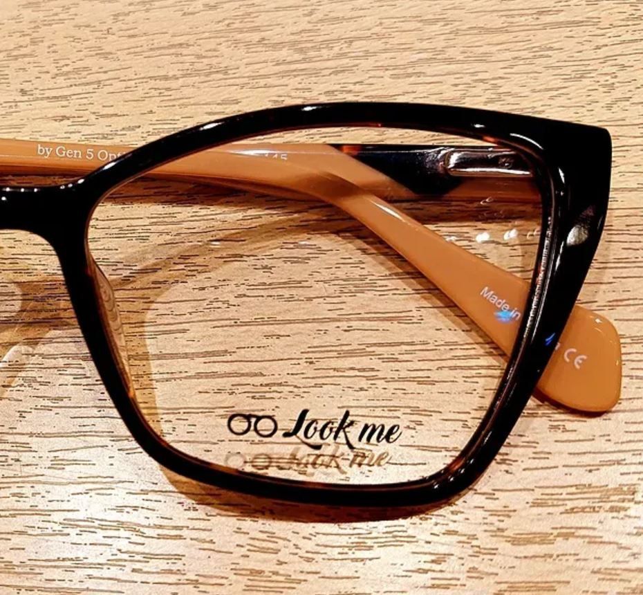 Gafas negras con patillas marrones que descansan sobre una superficie de madera.