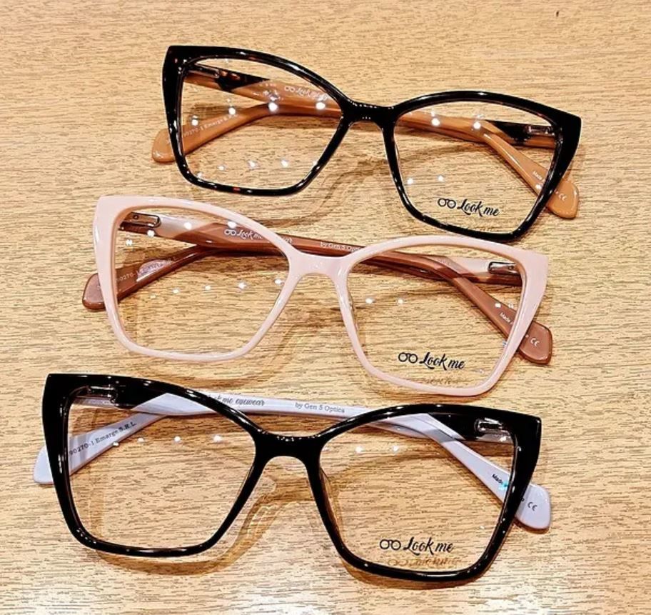 Tres pares de gafas de ojo de gato en negro, rosa palo y marrón sobre una superficie de madera.